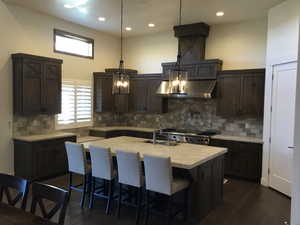 Kitchen featuring light countertops, a sink, a kitchen breakfast bar, and high end stainless steel range