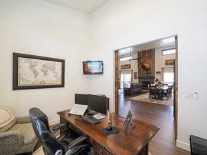 Office space with dark hardwood / wood-style flooring and a high ceiling