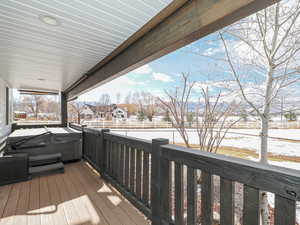 Snow covered deck featuring a hot tub