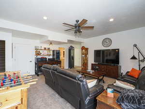 Living room featuring ceiling fan, light colored carpet, a textured ceiling, and bar