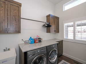 Clothes washing area with washing machine and dryer, dark wood-type flooring, sink, and cabinets