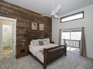 Carpeted bedroom featuring ceiling fan, access to outside, and wood walls