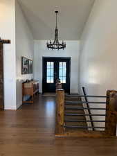 Entryway featuring french doors, a barn door, wood finished floors, high vaulted ceiling, and baseboards