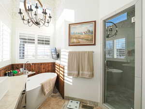 Bathroom featuring vanity, separate shower and tub, and a notable chandelier