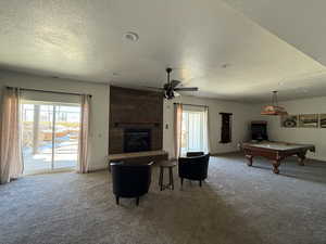 Carpeted living area with a large fireplace, baseboards, a textured ceiling, and pool table