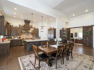 Dining space featuring vaulted ceiling, dark wood-type flooring, a barn door, and sink