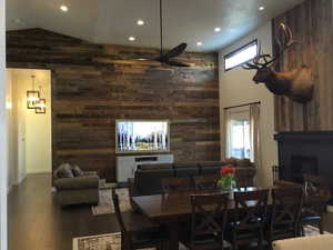 Dining area featuring a large fireplace, dark wood-style flooring, a wealth of natural light, and wooden walls