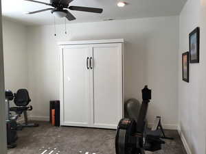 Exercise area featuring ceiling fan, carpet floors, visible vents, and baseboards