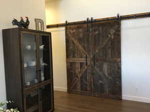 Interior space with a barn door, wood finished floors, and baseboards