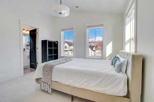 Carpeted bedroom with lofted ceiling and multiple windows