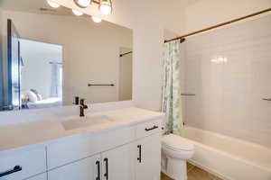 Full bathroom with tile patterned floors, toilet, vanity, and shower / tub combo with curtain