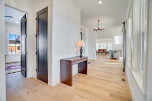 Corridor featuring light wood-type flooring and a chandelier