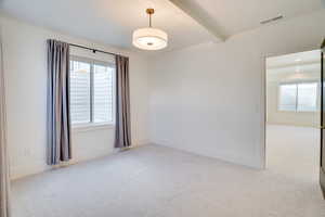 Carpeted empty room with beamed ceiling