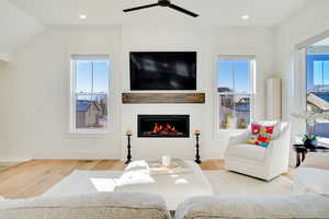 Living room with ceiling fan, vaulted ceiling, a wealth of natural light, and light hardwood / wood-style flooring