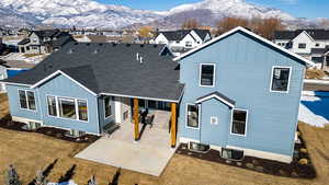 Snow covered back of property featuring a mountain view, a yard, and a patio