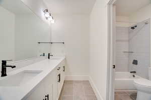 Full bathroom with toilet, tile patterned floors, vanity, and tiled shower / bath