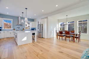 Kitchen with white cabinetry, wall chimney range hood, high quality fridge, and a center island