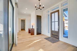 Entrance foyer with light wood-type flooring and an inviting chandelier