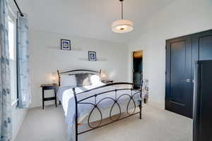 Bedroom featuring light carpet, a closet, vaulted ceiling, and refrigerator