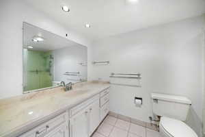 Bathroom with toilet, vanity, tile patterned flooring, and a shower with shower door