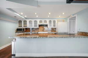 Kitchen featuring white cabinets, white refrigerator, backsplash, dark hardwood / wood-style floors, and kitchen peninsula