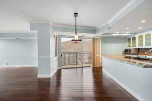 Unfurnished dining area featuring dark wood-type flooring and crown molding