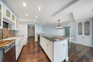 Kitchen with white cabinetry, appliances with stainless steel finishes, backsplash, dark stone counters, and pendant lighting