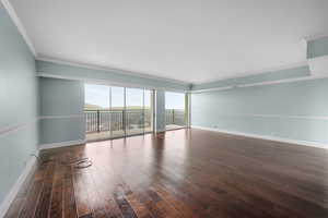 Empty room featuring crown molding and dark hardwood / wood-style floors