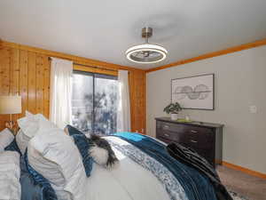 Bedroom featuring ornamental molding, wood walls, and carpet floors