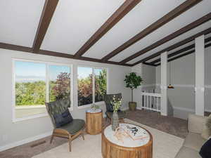 Living room featuring light colored carpet and vaulted ceiling with beams