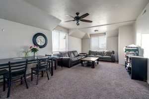 Carpeted living room with ceiling fan and a textured ceiling