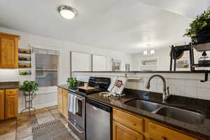 Kitchen with appliances with stainless steel finishes, lots of cabinets featuring space saving pullouts, dark granite counters, and sink