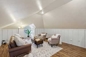 Den with vaulted ceiling and hardwood / wood-style floors