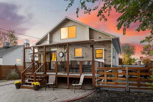 Back of house at dusk featuring composite deck and a patio area.