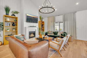 Living room with wood walls, light wood-type flooring, and vaulted ceiling