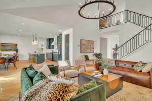 Living room featuring sink, an inviting chandelier, a towering ceiling, and light hardwood / wood-style floors