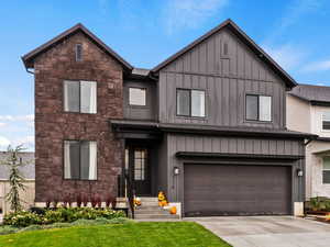 View of front facade with a front yard, a garage, and central air condition unit