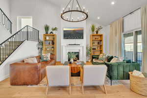 Living room featuring light wood-type flooring, a chandelier, and high vaulted ceiling