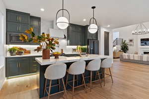 Kitchen with a center island with sink, high end fridge, tasteful backsplash, and pendant lighting