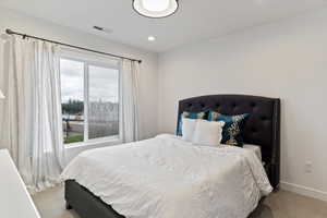 Bedroom featuring light colored carpet and multiple windows