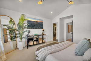 Bedroom with light colored carpet, vaulted ceiling, and ensuite bathroom