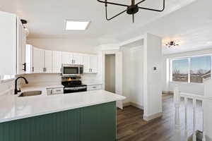 Kitchen featuring white cabinetry, kitchen peninsula, appliances with stainless steel finishes, vaulted ceiling, and sink