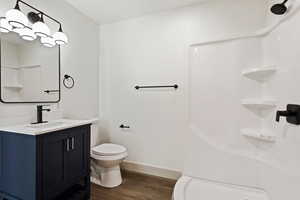 Bathroom featuring hardwood / wood-style flooring, toilet, vanity, and walk in shower