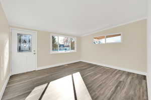 Entrance foyer featuring dark wood-type flooring and crown molding