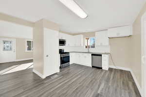 Kitchen featuring sink, white cabinetry, appliances with stainless steel finishes, and light wood-type flooring