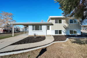 Split level home featuring a front yard, ac unit, and a carport