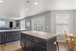 Kitchen featuring a kitchen island, light hardwood flooring, butcher block countertops, and barn sink