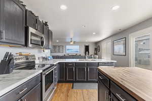 Kitchen with butcher block counters, hardwood style floors, butcher block countertop island, stainless steel appliances, and barn sink