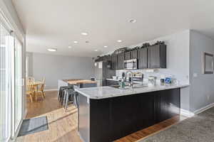 Kitchen with light wood-type flooring, kitchen peninsula, appliances with stainless steel finishes, and barn sink