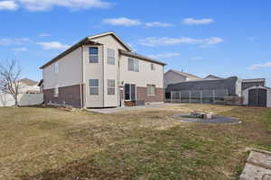 Fully fenced backyard with a lawn, a storage unit, a patio, and a fire pit